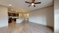 This single-floor residence offers a thoughtfully designed open-concept layout that seamlessly connects the living area and kitchen. Light wood-look luxury vinyl plank flooring runs throughout the main living spaces, complemented by neutral wall tones that create a bright, welcoming atmosphere. Ceiling fans are installed in both the living room and additional rooms, enhancing comfort and airflow.

The kitchen is a standout feature, showcasing rich dark espresso cabinetry with sleek hardware, granite countertops, a classic white subway tile backsplash, and a full suite of stainless steel appliances including a refrigerator with ice maker, electric range, and over-the-range microwave. A kitchen island with a sink and pendant lighting above adds both functionality and style, making it an ideal space for cooking and entertaining.

The living area is generously proportioned, with abundant natural light streaming through large windows and access to an exterior door. Bedrooms are carpeted for comfort and each features a window with blinds and a ceiling fan. The primary bathroom offers a dual-sink vanity with granite countertops, dark cabinetry, and a full tub-shower combination. A secondary bathroom includes a walk-in shower. A dedicated laundry room houses a full-size top-load washer and dryer, adding everyday convenience to this well-rounded home.