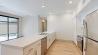 Located at 8000 Arlington Expressway in Jacksonville, FL, this well-appointed 2-bedroom, 2-bathroom residence offers a clean, contemporary design throughout its single-level layout. Light wood-style flooring flows consistently across all rooms, complemented by crisp white walls and recessed lighting that create a bright, welcoming atmosphere.

The open-concept living, dining, and kitchen area serves as the heart of the home. The kitchen is outfitted with white shaker-style cabinetry featuring brushed nickel hardware, a large peninsula with a white countertop and undermount sink, and a full suite of stainless steel appliances including a refrigerator, range, microwave, and dishwasher. Abundant recessed lighting illuminates the space effectively.

Both bathrooms are finished with white vanity cabinetry, white countertops, and framed mirrors. One bathroom features an accessible walk-in shower with grab bars, while the second includes a glass-enclosed shower stall. The bedrooms are generously sized, with large windows allowing ample natural light. The primary bedroom connects to a well-organized walk-in closet with wire shelving systems. A dedicated laundry area and multiple additional closets provide practical storage throughout. The hallway leads seamlessly between all rooms, reinforcing the unit's efficient and functional floor plan.