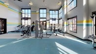 The Health Club at REVA Main St Rahway is a thoughtfully designed fitness facility located in Rahway, NJ, offering a comprehensive and energizing environment for residents and members alike. The main workout area impresses with dramatically high ceilings and floor-to-ceiling windows that flood the space with abundant natural light, while offering views of the surrounding neighborhood. Signature teal and yellow horizontal stripe accents run along the upper walls, reinforcing the facility's vibrant, modern aesthetic.

A striking large-scale mural depicting human figures in motion serves as a bold artistic focal point, covering an entire wall and adding dynamic visual energy to the training floor. The main gym area is equipped with a broad selection of strength machines, cable systems, free weights, and cardio equipment including rowing machines and stationary bikes, all arranged on teal-toned carpet flooring.

A dedicated studio space features a fleet of indoor cycling bikes, ceiling fans, bold teal and yellow color-blocked walls, and floor-to-ceiling mirrors, creating an immersive environment for group or solo cycling sessions. An adjacent functional training area provides TRX suspension systems, kettlebells, medicine balls, battle ropes, and a multi-purpose rig, catering to a wide range of training styles. A water fountain is conveniently located within the facility. Together, these spaces form a cohesive, well-appointed health club designed to support diverse fitness goals.