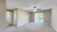Located at 1905 N Cunningham Ave in Urbana, IL, this two-bedroom, two-bathroom unit offers a well-designed single-floor layout that makes efficient use of its space. The living area is bright and open, featuring soft neutral-toned carpet, warm beige walls, and a ceiling fan with light fixture. A sliding glass door leads to a private balcony overlooking mature trees, allowing natural light to fill the room. The entry area transitions from tile flooring into the carpeted living space, with a ceiling fan adding comfort. The kitchen is equipped with dark espresso cabinetry, granite-style countertops, black appliances including a refrigerator and range, and durable tile flooring. A peninsula provides additional prep and serving space. The primary bedroom is generously sized, featuring carpet flooring, a ceiling fan, and a sliding glass door to the balcony. The second bedroom also offers carpet, a closet, and a window with outdoor views. Both bathrooms feature tile flooring and dark wood vanities with granite-style countertops. One bathroom includes a walk-in shower with framed glass doors, while the other offers a full tub-shower combination. The unit also includes a dedicated closet for added storage convenience.