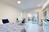 Located on the third floor at 615 W Nickerson St in Seattle's Queen Anne neighborhood, this efficiently designed studio unit makes excellent use of its compact footprint. The open-plan main area seamlessly integrates the living, dining, and kitchen zones into a single bright space. The kitchen features light wood cabinetry, a stainless steel refrigerator, dishwasher, and a clean white countertop with an undermount sink — all finished in a contemporary, minimal style. Light wood-tone flooring runs throughout, lending warmth and visual continuity across the unit. Large sliding glass doors connect the living area to a private balcony, flooding the interior with natural light and offering neighborhood views. A dedicated workspace nook near the balcony benefits from an additional window, creating a well-lit area ideal for a desk setup. The unit includes a full bathroom with a soaking tub and clean white tile surround. A convenient in-unit laundry closet with stacked washer and dryer is tucked along the hallway, along with a separate closet for storage. Recessed lighting throughout the unit ensures consistent, functional illumination. The overall aesthetic is modern and clean, with neutral tones and thoughtful spatial planning making this a practical and comfortable urban residence.