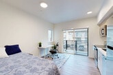 Located on the third floor at 615 W Nickerson St in Seattle's Queen Anne neighborhood, this efficiently designed studio unit makes excellent use of its compact footprint. The open-plan main area seamlessly integrates the living, dining, and kitchen zones into a single bright space. The kitchen features light wood cabinetry, a stainless steel refrigerator, dishwasher, and a clean white countertop with an undermount sink — all finished in a contemporary, minimal style. Light wood-tone flooring runs throughout, lending warmth and visual continuity across the unit. Large sliding glass doors connect the living area to a private balcony, flooding the interior with natural light and offering neighborhood views. A dedicated workspace nook near the balcony benefits from an additional window, creating a well-lit area ideal for a desk setup. The unit includes a full bathroom with a soaking tub and clean white tile surround. A convenient in-unit laundry closet with stacked washer and dryer is tucked along the hallway, along with a separate closet for storage. Recessed lighting throughout the unit ensures consistent, functional illumination. The overall aesthetic is modern and clean, with neutral tones and thoughtful spatial planning making this a practical and comfortable urban residence.