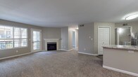 This single-floor residence offers a well-designed, open-concept layout that seamlessly connects the living, dining, and kitchen areas. The spacious living room is finished with plush wall-to-wall carpeting and neutral taupe-toned walls, anchored by a classic fireplace with a white marble-style surround — a standout architectural feature that adds warmth and character. A glass-paneled exterior door allows natural light to filter into the living space.

The kitchen is efficiently designed with white cabinetry, granite-style countertops, and a full suite of stainless steel appliances including a refrigerator, electric range, and microwave. A peninsula counter with panel detailing provides a natural transition between the kitchen and living areas, while wood-look vinyl flooring adds a clean, durable finish underfoot.

The unit includes multiple generously sized bedrooms, each featuring soft carpeting and ample closet space. One bedroom features an en-suite bathroom connection, enhancing privacy and convenience. Both bathrooms are finished with white tile surrounds in the tub/shower areas, and one features wood-look vinyl flooring for a modern touch.

Throughout the space, consistent neutral tones, white trim, and panel-style doors create a cohesive and move-in-ready aesthetic. HVAC vents are integrated throughout, ensuring year-round comfort.