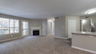This single-floor residence offers a well-designed, open-concept layout that seamlessly connects the living, dining, and kitchen areas. The spacious living room is finished with plush wall-to-wall carpeting and neutral taupe-toned walls, anchored by a classic fireplace with a white marble-style surround — a standout architectural feature that adds warmth and character. A glass-paneled exterior door allows natural light to filter into the living space.

The kitchen is efficiently designed with white cabinetry, granite-style countertops, and a full suite of stainless steel appliances including a refrigerator, electric range, and microwave. A peninsula counter with panel detailing provides a natural transition between the kitchen and living areas, while wood-look vinyl flooring adds a clean, durable finish underfoot.

The unit includes multiple generously sized bedrooms, each featuring soft carpeting and ample closet space. One bedroom features an en-suite bathroom connection, enhancing privacy and convenience. Both bathrooms are finished with white tile surrounds in the tub/shower areas, and one features wood-look vinyl flooring for a modern touch.

Throughout the space, consistent neutral tones, white trim, and panel-style doors create a cohesive and move-in-ready aesthetic. HVAC vents are integrated throughout, ensuring year-round comfort.