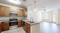 Located at Two Addison Place in Pooler, Georgia, this single-floor residence offers a thoughtfully designed layout with consistent, quality finishes throughout. The kitchen serves as a central highlight, featuring warm honey-toned cabinetry, granite countertops, and a full suite of stainless steel appliances including a refrigerator, range, microwave, and dishwasher. A peninsula with a double undermount sink and pendant lighting overhead creates an ideal space for meal prep and casual dining, while opening naturally toward the living area — a bright, open space finished with light wood-style flooring and a ceiling fan. The bedroom areas are carpeted for comfort, each with neutral walls and ceiling fans that promote airflow and relaxation. Natural light filters in through window blinds, giving the rooms a warm, inviting feel. The bathroom is clean and functional, offering a granite-topped vanity with warm wood cabinetry, a full soaking tub with shower, and the same light wood-style flooring found throughout the common areas. The open-concept flow between the kitchen, dining, and living spaces makes this residence feel connected and spacious, while the consistent use of granite surfaces and stainless fixtures lends a cohesive, modern aesthetic throughout.