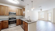 Located at Two Addison Place in Pooler, Georgia, this single-floor residence offers a thoughtfully designed layout with consistent, quality finishes throughout. The kitchen serves as a central highlight, featuring warm honey-toned cabinetry, granite countertops, and a full suite of stainless steel appliances including a refrigerator, range, microwave, and dishwasher. A peninsula with a double undermount sink and pendant lighting overhead creates an ideal space for meal prep and casual dining, while opening naturally toward the living area — a bright, open space finished with light wood-style flooring and a ceiling fan. The bedroom areas are carpeted for comfort, each with neutral walls and ceiling fans that promote airflow and relaxation. Natural light filters in through window blinds, giving the rooms a warm, inviting feel. The bathroom is clean and functional, offering a granite-topped vanity with warm wood cabinetry, a full soaking tub with shower, and the same light wood-style flooring found throughout the common areas. The open-concept flow between the kitchen, dining, and living spaces makes this residence feel connected and spacious, while the consistent use of granite surfaces and stainless fixtures lends a cohesive, modern aesthetic throughout.