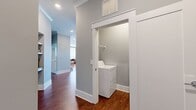 This single-story residence offers a thoughtful layout within its 1,210 square feet of living space. The home features two bedrooms, including a generously sized primary bedroom of 190 square feet, and an impressive four bathrooms, ensuring ample convenience for residents and guests alike.

The living area, as shown in the image, showcases a harmonious blend of style and comfort. Rich hardwood floors provide a warm foundation, complemented by deep green walls that create a sophisticated ambiance. A large window floods the space with natural light, while white trim adds a crisp contrast to the bold wall color.

The furniture arrangement demonstrates a balance of form and function. A plush gray sofa anchors the seating area, flanked by two modern armchairs with light-colored frames and dark upholstery. A unique oval coffee table in a light hue serves as a focal point, adorned with a sculptural accent piece.

The vibrant area rug introduces a splash of warm colors and intricate patterns, tying the room together and adding visual interest. A sleek floor lamp provides additional lighting options for various moods and activities.

This home's layout includes dedicated spaces for laundry and storage, with two closets and a separate laundry room. The open-concept design likely combines the kitchen and living areas, promoting a spacious feel and easy flow for entertaining and daily life.