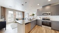 Located at 7501 Jefferson St NE in Albuquerque, NM, this modern 1-bedroom, 2-bathroom residence offers a thoughtfully designed open-concept layout. The combined kitchen and living area serves as the heart of the home, where sleek gray cabinetry with brushed hardware pairs with crisp white quartz countertops and a full stainless steel appliance suite, including a French door refrigerator, range, microwave, and dishwasher. Pendant lighting and a white subway tile backsplash add contemporary character, while light-toned hardwood-style flooring flows seamlessly throughout. The living area is bright and inviting, benefiting from generous natural light through large windows with outdoor views. A private balcony extends the living space outdoors. The bedroom is a calm retreat, featuring a ceiling fan, a sizable window with natural light, and ample room for furnishings. The primary bathroom features a navy blue vanity with a granite-style countertop, a soaking tub with tiled surround, and hardwood-style flooring. A second full bathroom provides added convenience. A dedicated in-unit laundry area with a stacked washer and dryer adds everyday practicality. The hallway connects all areas efficiently, completing this well-appointed residence.