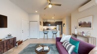 This thoughtfully designed 2-bedroom, 2-bathroom residence in Silverdale, WA offers a contemporary open-concept layout that seamlessly connects the living, dining, and kitchen areas. Light wood-style flooring flows throughout the main living space, complemented by recessed lighting, a ceiling fan, and a wall-mounted mini-split system for year-round comfort. Large windows flood the living room with natural light and provide views of the surrounding neighborhood, while a private balcony extends the living space outdoors.

The kitchen is a standout feature, showcasing dark cabinetry with sleek hardware, quartz countertops, stainless steel appliances including a gas range, and elegant pendant lighting over a breakfast bar with seating for two.

The spacious primary bedroom offers plush carpeting, generous proportions, a walk-in closet with built-in shelving, and a private en-suite bathroom. The second bedroom is bright and comfortable, also carpeted, with easy access to the second full bathroom. Both bathrooms are finished with dark wood vanities and clean white countertops.

Additional highlights include two closets, a dedicated laundry area, and a welcoming hallway entry. The overall aesthetic is clean, modern, and functional throughout.