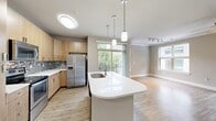 Located at 510 N Wilmington St in Raleigh, NC, this thoughtfully designed two-bedroom, two-bathroom residence delivers a comfortable and modern living experience on a single floor. The open-concept kitchen and living area serves as the heart of the home, featuring light wood cabinetry, stainless steel appliances, a mosaic tile backsplash, and a white quartz island with pendant lighting overhead. Large windows and a sliding glass door flood the living area with natural light and provide direct access to a private balcony with tree-lined views. Hardwood-style flooring runs throughout the main living spaces, complementing the warm, neutral color palette. The bedrooms offer plush carpeting, ceiling fans, and generous windows that invite outdoor views and natural light. The primary bedroom includes its own closet space, while the residence boasts five closets in total, ensuring ample storage throughout. The bathrooms are finished with tile flooring, wood-toned vanities, white countertops, and arched architectural detailing. A dedicated laundry area and utility room add everyday convenience. Well-lit hallways with crown molding connect each area of the home, creating a cohesive and polished interior throughout.