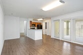 This single-floor, 1-bedroom, 1-bathroom unit offers a thoughtfully designed layout that maximizes functionality and comfort. The open-concept living and kitchen area forms the heart of the home, featuring warm hardwood-style flooring that runs throughout the main living spaces. Large windows with blinds allow ample natural light to fill the room, creating a bright and welcoming atmosphere.

The kitchen is well-equipped with rich wood cabinetry, granite-style countertops, and a full suite of black appliances, including a refrigerator, range, microwave, and dishwasher. A convenient in-unit washer and dryer is tucked behind louvered closet doors adjacent to the kitchen. A peninsula counter provides additional workspace and separates the kitchen from the living area.

The spacious bedroom is carpeted for comfort and includes a ceiling fan, a natural light window with an outdoor view, and direct access to a dedicated closet with built-in shelving. Crown molding adds a refined architectural detail to the bedroom space.

The bathroom features a granite-topped vanity with warm wood cabinetry, a full soaking tub with tiled surround, and grab bars for added accessibility. The consistent use of light, neutral tones throughout the unit creates a clean and cohesive aesthetic.