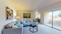This single-floor residence offers a thoughtfully arranged layout across several well-defined living spaces. The open-concept living and dining area serves as the heart of the home, featuring soft wall-to-wall carpeting, neutral walls, and an abundance of natural light. A large sliding glass door connects the living room directly to a private balcony, allowing for seamless indoor-outdoor flow and views of the surrounding greenery.

Adjacent to the living area, the dining space comfortably accommodates a full dining set and benefits from the same bright, open atmosphere. The galley-style kitchen is equipped with warm wood cabinetry, a gas range, built-in microwave, full-size refrigerator, and hardwood-style flooring, providing a practical and efficient cooking environment. In-unit laundry is also accessible from the kitchen area.

The residence includes two bedrooms, each carpeted and generously sized with ample closet storage and windows that bring in natural light. The primary bedroom offers a calm, spacious retreat. A full bathroom features a tub-shower combination, wood-style flooring, and a clean white vanity. A secondary flexible room with closet space adds versatility to the overall layout.