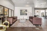 Located at 173 E Mallard Dr in Boise, Idaho, this single-floor community clubhouse delivers a polished, contemporary atmosphere designed for both socializing and productivity. The main lounge area is an open, generously proportioned space anchored by large-format tile flooring, elevated ceilings, and structural columns that define distinct zones without sacrificing the sense of openness. Comfortable seating arrangements — including plush sofas, accent chairs, and a patterned ottoman — are thoughtfully positioned throughout, complemented by curated artwork and modern sculptural décor.

A glass-partitioned conference room provides a semi-private workspace, offering visibility into the lounge while maintaining a focused environment. Adjacent to the lounge, a cozy seating nook with upholstered chairs creates an intimate retreat, ideal for small group conversations.

The kitchen area features a wraparound bar counter with seating, rich wood cabinetry, white tile backsplash, light quartz countertops, and stainless steel appliances — well-suited for hosting and casual gatherings.

A standout feature is the dedicated screening room, outfitted with rows of fixed theater-style seating, carpeted flooring, and bold branded wall décor, providing a unique entertainment space. Large windows throughout the clubhouse invite natural light, enhancing the overall warm and welcoming ambiance of this well-appointed community facility.