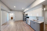 Located at 100 Hemenway Street in Boston's Fenway neighborhood, this three-bedroom, two-bathroom unit offers a well-designed, modern interior across a single floor. The open-concept kitchen, dining, and living area serves as the heart of the home, featuring light hardwood-style flooring, recessed lighting, and a sleek, contemporary kitchen equipped with stainless steel appliances including a refrigerator, range, microwave, and dishwasher. Cabinetry combines high-gloss white upper cabinets with matte gray lower cabinets, complemented by light stone countertops and a subway tile backsplash. The three bedrooms are carpeted for comfort, each featuring neutral gray walls and windows that invite natural light and neighborhood views. The primary bedroom includes a double closet with paneled doors and matte black hardware. The unit features four closets total, providing ample storage throughout. The two bathrooms are finished with modern tile flooring and wood-toned vanities topped with stone counters. The full bathroom includes a windowed walk-in shower with classic subway tile surround, while the second bathroom offers a clean, functional layout. A dedicated entrance and a consistent neutral color palette throughout give the unit a cohesive, contemporary feel.