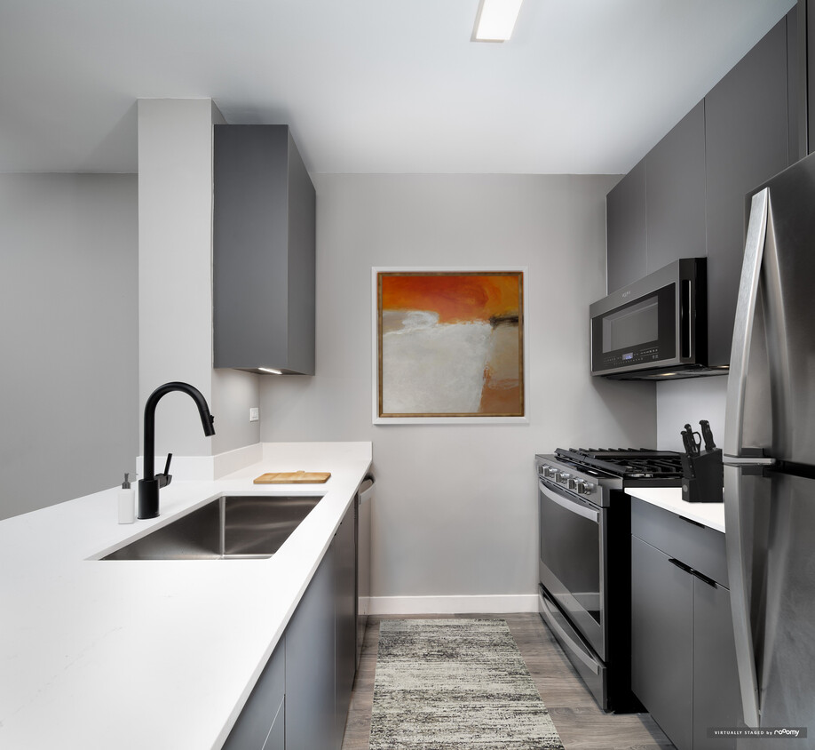 Renovated Package II kitchen with white quartz countertop and backsplash, upgraded stainless steel appliances, upgraded black hardware, and upgraded lighting - Avalon Midtown West