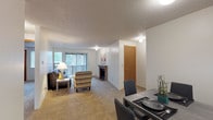 This single-floor residence offers a thoughtfully designed layout that balances comfort and functionality throughout. The open-concept living and dining area serves as the heart of the home, centered around a classic brick fireplace that anchors the space with warmth and character. Soft carpeting flows underfoot, while a large sliding glass door with vertical blinds fills the living room with natural light and provides access to an outdoor balcony with greenery views.

Adjacent to the living area, the galley-style kitchen is efficiently organized with warm wood cabinetry, dark granite-style countertops, tile flooring, and a full suite of white appliances including a range, dishwasher, and refrigerator. Ample upper and lower cabinet storage ensures practical everyday use.

The two bedrooms are generously sized, each featuring plush carpeting, natural window light, and walk-in closets that provide substantial storage. The textured ceilings are consistent throughout the residence, adding a classic residential feel.

Two full bathrooms serve the home, both finished with warm wood vanities, dark countertops, mirrored medicine cabinets, and tile flooring. One bathroom includes a shower-tub combination, while the other is configured with additional storage and a separate water closet. Together, these spaces deliver a comfortable and practical living environment.