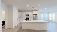 Located at 1801 Riverside Parkway in Douglasville, GA, this well-appointed 2-bedroom, 2-bathroom residence offers a thoughtfully designed single-level layout with modern finishes throughout. The open-concept kitchen serves as the heart of the home, showcasing crisp white shaker cabinetry with matte black hardware, a subway tile backsplash, gleaming quartz countertops, and a large center island with an integrated sink. Stainless steel appliances — including a refrigerator, range, microwave, and dishwasher — complete the space, while in-unit laundry adds everyday convenience. Light wood-tone flooring flows through the main living and kitchen areas, complemented by recessed lighting and large windows that invite natural light. The spacious living area features clean white walls and additional windows with views to the outdoors. The primary bedroom is generously sized, complete with a ceiling fan, plush carpeting, a private en-suite bathroom, and a walk-in closet outfitted with wire shelving systems. The second bedroom mirrors the same comfortable feel with carpet and a ceiling fan. Both bathrooms feature tile flooring, white vanities, and tiled tub-shower combinations. A second walk-in closet provides ample additional storage, rounding out this clean, contemporary residence.