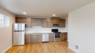 This single-floor unit offers a practical and efficiently designed layout across three bedrooms and two bathrooms. Light hardwood-style flooring runs consistently throughout, complementing the neutral, off-white wall tones that lend a clean, modern aesthetic to every room.

The kitchen is well-appointed with warm-toned wood cabinetry, white countertops, and a full suite of stainless steel appliances including a refrigerator, gas range, built-in microwave, and dishwasher. Recessed lighting illuminates the space effectively. An adjacent hallway houses a stacked washer and dryer, providing convenient in-unit laundry.

The combined living area is bright and open, benefiting from multiple windows with slatted blinds that allow natural light while maintaining privacy. Outdoor views of the surrounding neighborhood are visible from several rooms.

The primary bedroom offers a comfortable footprint, while the two additional bedrooms are functional and well-lit, each with windows. Wall-mounted heating units are present in the bedrooms. Both bathrooms are clean and straightforward, with one featuring a full tub-shower combination, wood-toned vanity, and light flooring consistent with the rest of the unit.