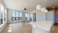 Located at 514 W Washington Ave in the heart of Madison, WI, this modern two-floor residence delivers a clean, contemporary aesthetic across every room. Light wood-tone flooring runs throughout both levels, complementing the neutral palette of crisp white walls and trim.

The open-concept kitchen is a standout, outfitted with white shaker cabinetry, a herringbone tile backsplash, stainless steel appliances, and a central island with pendant lighting overhead. Large windows flood the space with natural light and offer views of the surrounding cityscape. The adjoining living area is equally bright, featuring a ceiling fan, a stylish barn door, and expansive windows that frame outdoor views.

The bedrooms are generously proportioned and sun-filled, each featuring ceiling fans and wide windows with city or treetop views. The bathrooms are well-appointed — one features a light blue vanity with quartz countertops and a glass-enclosed shower, while another offers a clean, minimalist design with brushed gold fixtures and a wide vanity mirror.

A hallway with a window at its end adds a bright, airy feel to the interior flow. Additional conveniences include an in-unit laundry closet with a stacked washer and dryer. The overall ambiance is fresh, modern, and move-in ready.