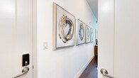 Located at 800 N 2nd St in Phoenix, AZ, this efficiently designed one-bedroom, one-bathroom residence makes the most of its compact footprint through thoughtful layout and smart storage solutions. The entry hallway sets an artistic tone immediately, lined with a curated series of abstract framed artwork and rich hardwood-style flooring that flows throughout the entire space.

The main living area and bedroom are seamlessly integrated, anchored by a built-in Murphy bed with flanking shelving units that maximize both functionality and style. Natural light fills the room through large windows, offering views of greenery outside. Crisp white walls contrast warmly with the dark wood flooring, creating a bright yet grounded ambiance.

The kitchen is neatly tucked along one wall, featuring white cabinetry, a subway tile backsplash, stainless steel appliances including a full-size refrigerator, microwave, and dishwasher, providing full functionality in a compact form.

The bathroom is clean and contemporary, with a glass-enclosed shower, white vanity with ample storage, and wood-look tile flooring consistent with the rest of the unit. Curated artwork continues here, reinforcing the cohesive modern aesthetic found throughout the space.

Overall, this unit delivers a polished, gallery-like atmosphere designed for efficient, stylish urban living in the heart of Phoenix.