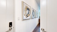 Located at 800 N 2nd St in Phoenix, AZ, this efficiently designed one-bedroom, one-bathroom residence makes the most of its compact footprint through thoughtful layout and smart storage solutions. The entry hallway sets an artistic tone immediately, lined with a curated series of abstract framed artwork and rich hardwood-style flooring that flows throughout the entire space.

The main living area and bedroom are seamlessly integrated, anchored by a built-in Murphy bed with flanking shelving units that maximize both functionality and style. Natural light fills the room through large windows, offering views of greenery outside. Crisp white walls contrast warmly with the dark wood flooring, creating a bright yet grounded ambiance.

The kitchen is neatly tucked along one wall, featuring white cabinetry, a subway tile backsplash, stainless steel appliances including a full-size refrigerator, microwave, and dishwasher, providing full functionality in a compact form.

The bathroom is clean and contemporary, with a glass-enclosed shower, white vanity with ample storage, and wood-look tile flooring consistent with the rest of the unit. Curated artwork continues here, reinforcing the cohesive modern aesthetic found throughout the space.

Overall, this unit delivers a polished, gallery-like atmosphere designed for efficient, stylish urban living in the heart of Phoenix.