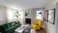 This single-floor space showcases a thoughtfully designed living area that combines comfort and contemporary style. The living room serves as the heart of the home, anchored by a classic tile-surround fireplace that adds warmth and architectural character to the room. Hardwood flooring runs throughout, providing a rich, durable foundation that complements the space's eclectic aesthetic.

Natural light pours in generously through multiple windows dressed with sheer, patterned curtains, creating a bright and welcoming atmosphere. The interior design is bold and expressive, featuring a deep green velvet sofa paired with a striking yellow wingback chair, accented by a vibrant navy and blue patterned area rug. A sleek white coffee table and an oversized arc floor lamp add functional yet stylish elements to the room.

Lush indoor greenery, including a large fiddle leaf fig plant, introduces a natural, organic touch to the living space. A prominent piece of abstract wall art displayed above the fireplace adds a creative focal point. The textured ceiling adds a layer of visual interest to the overall design. The space is cohesive and well-curated, offering a lively yet comfortable environment ideal for both relaxing and entertaining.