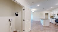 Located at 100 Farm Creek Rd in Enterprise, Alabama, this single-story 2-bedroom, 2-bathroom home offers a clean, modern aesthetic with thoughtful finishes throughout. The open-concept kitchen and living area serves as the heart of the home, showcasing light hardwood-style flooring, recessed lighting, and a elegant chandelier. The kitchen is well-equipped with crisp white shaker cabinets, granite countertops, stainless steel appliances including a range, microwave, and refrigerator, and a central island that provides additional workspace and storage. A dedicated pantry and utility closet add practical functionality. Crown molding is present throughout, lending a polished, refined character to each room. The two bedrooms feature plush carpeting, large windows that invite natural light and outdoor views, and dedicated closets. The primary bedroom includes a ceiling fan for added comfort. Both bathrooms are finished with granite-topped vanities, white cabinetry, and hardwood-style flooring; one bathroom features a full soaking tub with a tiled surround and brushed nickel fixtures. A connecting hallway ties the layout together efficiently. The overall design palette of soft neutrals and white trim creates a bright, welcoming atmosphere throughout.