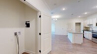 Located at 100 Farm Creek Rd in Enterprise, Alabama, this single-story 2-bedroom, 2-bathroom home offers a clean, modern aesthetic with thoughtful finishes throughout. The open-concept kitchen and living area serves as the heart of the home, showcasing light hardwood-style flooring, recessed lighting, and a elegant chandelier. The kitchen is well-equipped with crisp white shaker cabinets, granite countertops, stainless steel appliances including a range, microwave, and refrigerator, and a central island that provides additional workspace and storage. A dedicated pantry and utility closet add practical functionality. Crown molding is present throughout, lending a polished, refined character to each room. The two bedrooms feature plush carpeting, large windows that invite natural light and outdoor views, and dedicated closets. The primary bedroom includes a ceiling fan for added comfort. Both bathrooms are finished with granite-topped vanities, white cabinetry, and hardwood-style flooring; one bathroom features a full soaking tub with a tiled surround and brushed nickel fixtures. A connecting hallway ties the layout together efficiently. The overall design palette of soft neutrals and white trim creates a bright, welcoming atmosphere throughout.