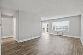 This single-story residence offers a thoughtfully designed layout comprising one bedroom, two bathrooms, a living room, kitchen, and hallway. The open living area is a standout feature, showcasing wide-plank wood-style flooring, neutral gray walls, and a textured ceiling. Natural light filters in generously through horizontal-slatted blinds and a sliding glass door that opens to a balcony, creating a bright and airy atmosphere. A wall-mounted HVAC unit provides in-unit climate control.

The galley-style kitchen is well-equipped with white shaker cabinets, quartz countertops, a gray subway tile backsplash, stainless steel appliances including a gas range and dishwasher, and wood-style flooring that carries through seamlessly.

The bedroom features plush wall-to-wall carpeting, a window for natural light, and a mirrored sliding-door closet offering practical storage. A second room with wood-style flooring provides additional flexible living space.

Both bathrooms are cleanly finished; one features a full tub-shower combo with wood-style flooring, while the other includes a sleek white vanity with ample cabinetry, quartz counters, and a large mirror. Clean white trim and a consistent neutral palette throughout give the entire space a cohesive, modern feel.