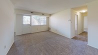 This single-floor residence at 3400 Miller Rd in Wilmington, Delaware offers a practical and well-organized layout across multiple rooms. The spacious living area is carpeted throughout and features large windows that allow abundant natural light to fill the space, along with direct access to an exterior door — ideal for easy entry and outdoor connectivity. The galley-style kitchen is efficiently designed with warm wood cabinetry lining both sides, white appliances including a gas range, dishwasher, and refrigerator, complemented by light-toned countertops and durable wood-look flooring. Multiple bedrooms are generously sized, each featuring plush carpeting, large windows with views of surrounding greenery, and neutral white walls that create a clean, versatile backdrop. At least one bedroom includes a walk-in closet, providing ample storage. The bathrooms are finished with classic white tile, including a tiled tub and shower surround, mosaic tile flooring, and safety grab bars, offering a clean and functional design. Throughout the residence, the consistent neutral color palette and practical finishes create a cohesive and comfortable living environment.
