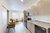 This thoughtfully designed 1-bedroom, 3-bathroom residence makes efficient use of its single-floor layout, offering a well-organized living experience with contemporary finishes throughout. Wood-look plank flooring runs seamlessly across the space, lending warmth and visual continuity from room to room.

The open-concept kitchen is outfitted with light wood cabinetry extending to the ceiling for ample storage, granite-style countertops, a stainless steel sink, and a full suite of black appliances including a refrigerator, electric range, built-in microwave, and dishwasher. The kitchen flows naturally into the dining and living area, which benefits from a large window that invites natural light and provides views of the surrounding neighborhood.

The bedroom is a serene retreat with tall ceilings, a well-placed window with blinds, and wood-look flooring. An adjacent utility room houses a full-size side-by-side washer and dryer alongside built-in shelving, adding notable convenience. The three bathrooms are finished with granite-style vanity countertops, light wood cabinetry, and walk-in shower stalls with clean white surrounds. The entry area features a full-size closet with built-in shelving and soaring ceiling height that enhances the sense of openness throughout this efficiently planned residence.