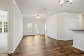 This single-story, three-bedroom, two-bathroom home offers a thoughtfully designed layout across a comfortable footprint. Wood-look flooring runs throughout the main living areas, complemented by crown molding details that add a refined touch to the living room and dining area. The living room connects seamlessly to a dedicated dining space, which features a chandelier, crown molding, and a glass door that invites natural light and provides outdoor access.

The galley-style kitchen is well-equipped with white cabinetry, dark granite-style countertops, a double stainless steel sink, and stainless steel appliances, including a range and microwave. A breakfast bar separates the kitchen from the adjoining areas, adding functional versatility.

The primary bedroom features plush carpeting, an en-suite bathroom with a dark countertop vanity and tiled tub-shower combination, and a walk-in closet with wire shelving. The two secondary bedrooms are also carpeted and include closets with built-in shelving. A dedicated laundry room with hookups and overhead wire shelving adds everyday convenience. The second full bathroom mirrors the primary in its clean, functional design.