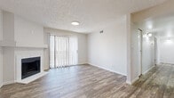 This single-floor residence presents a clean, neutral aesthetic throughout its well-organized layout. The living room serves as a central gathering space, finished with wood-look plank flooring and anchored by a white-surround fireplace. Sliding glass doors fitted with vertical blinds allow natural light to fill the room while providing access to an outdoor area. A textured ceiling adds subtle architectural character to the space.

The kitchen is thoughtfully designed in a galley configuration, featuring white shaker-style cabinetry with matte black hardware, light quartz countertops, and a full suite of stainless steel appliances including a range, microwave, refrigerator, and dishwasher. A pass-through counter connects the kitchen to an adjacent dining or flex area, which shares the same warm wood-look flooring.

The bedrooms are finished with plush carpeting and receive natural light through windows and sliding glass doors. Each room includes closet storage, and ceiling fans are present for added comfort. The bathrooms are clean and functional, each featuring a full tub and shower combination with brushed hardware, wood-look flooring, and crisp white finishes throughout.