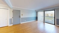 Located at 2921 W Clark Rd in Ypsilanti, Michigan, this second-floor one-bedroom, one-bathroom unit offers a thoughtfully designed layout that makes efficient use of its space. Throughout the unit, warm-toned hardwood-style flooring flows seamlessly, complemented by a consistent two-tone wall treatment featuring a soft blue-gray lower half beneath a lighter upper half, accented by clean white crown molding and baseboards.

The open living room is bright and inviting, anchored by a sliding glass door that leads to a private balcony with outdoor views, allowing natural light to fill the space. The galley-style kitchen is well-equipped with white shaker cabinetry, dark granite countertops, stainless steel appliances including a refrigerator and dishwasher, and a stainless steel sink — all finished with the same warm flooring underfoot.

The bedroom is a comfortable size, featuring a window with outdoor views, the same two-tone wall treatment, and notably generous closet space with two sets of double sliding closet doors providing ample storage.

The bathroom is clean and functional, featuring light tile flooring, a rich wood-toned vanity with a granite countertop, a tub-shower combination, and brushed nickel grab bars and fixtures throughout.