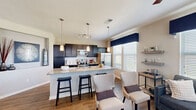Located in Parker, Colorado, this well-appointed 2-bedroom, 2-bathroom single-story home offers a thoughtfully designed open-concept layout that maximizes both comfort and functionality. The heart of the home is the chef-inspired kitchen, featuring dark espresso cabinetry, granite countertops, a subway tile backsplash, stainless steel appliances, and a generous island with bar seating — all illuminated by stylish pendant lighting. Hardwood-style flooring flows seamlessly through the kitchen, dining, and living areas, creating a cohesive and modern aesthetic. The dining area is accented by a bold navy feature wall and large windows that invite abundant natural light. The living room continues the bright, airy feel with multiple windows dressed in elegant drapery. The spacious primary bedroom features plush carpeting, a ceiling fan, and a private en-suite bathroom complete with dual granite vanities and a soaking tub. The second bedroom offers a warm, inviting atmosphere with a closet and soft carpeting. A second full bathroom serves the remaining living spaces. Throughout the home, neutral tones are complemented by navy blue accents, creating a polished and cohesive design. This home combines practical layout with upscale finishes in a desirable Parker location.