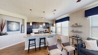 Located in Parker, Colorado, this well-appointed 2-bedroom, 2-bathroom single-story home offers a thoughtfully designed open-concept layout that maximizes both comfort and functionality. The heart of the home is the chef-inspired kitchen, featuring dark espresso cabinetry, granite countertops, a subway tile backsplash, stainless steel appliances, and a generous island with bar seating — all illuminated by stylish pendant lighting. Hardwood-style flooring flows seamlessly through the kitchen, dining, and living areas, creating a cohesive and modern aesthetic. The dining area is accented by a bold navy feature wall and large windows that invite abundant natural light. The living room continues the bright, airy feel with multiple windows dressed in elegant drapery. The spacious primary bedroom features plush carpeting, a ceiling fan, and a private en-suite bathroom complete with dual granite vanities and a soaking tub. The second bedroom offers a warm, inviting atmosphere with a closet and soft carpeting. A second full bathroom serves the remaining living spaces. Throughout the home, neutral tones are complemented by navy blue accents, creating a polished and cohesive design. This home combines practical layout with upscale finishes in a desirable Parker location.