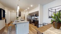 This well-appointed single-floor residence offers a thoughtfully designed open-concept layout that seamlessly connects the kitchen, dining, and living areas. The kitchen is a standout feature, equipped with stainless steel appliances including a refrigerator, range, dishwasher, and over-the-range microwave. Dark espresso cabinetry pairs elegantly with granite countertops, while a central island with a sink and pendant lighting serves as both a functional workspace and a casual gathering spot. Wood-style flooring flows throughout the main living areas, adding warmth and continuity.

The dining area is adjacent to the kitchen and includes built-in open shelving, offering both display and storage functionality. The living room is bright and inviting, featuring a sliding glass door that opens to a private balcony with outdoor views. The bedrooms are carpeted for comfort, with generous natural light provided by large windows with blinds and curtains. The bathroom is finished with granite countertops, dark cabinetry, a large vanity mirror, and a tub-shower combination. A dedicated utility area houses the water heater and electrical panel. The overall aesthetic is clean, contemporary, and functional throughout.