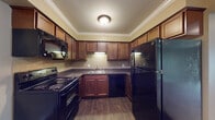 This single-floor residence in Riverview, Michigan offers a well-organized layout with two bedrooms and two full bathrooms. The kitchen is designed for practicality, featuring rich medium-toned wood cabinetry extending to the ceiling, dark granite-style countertops, a tile backsplash, and a full suite of black appliances including a range, over-the-range microwave, dishwasher, and refrigerator. Wood-style flooring grounds the kitchen, while crown molding adds a refined finishing detail.

The living area is carpeted and benefits from recessed lighting and crown molding throughout. A sliding glass door with vertical blinds provides natural light and outdoor access. A pass-through counter connects the living space to the kitchen, which also features a ceiling fan for added comfort.

The bedrooms are carpeted with neutral warm tones, offering ample natural light through large windows fitted with vertical blinds. One bedroom includes a generously sized walk-in closet outfitted with wire shelving systems for organized storage.

The bathrooms feature tile flooring, wood vanity cabinetry with dark countertops, and a tub-shower combination. Crown molding and consistent neutral wall tones carry throughout the unit, providing a cohesive and comfortable living environment.