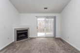 This single-floor residence is designed with an open, functional layout that connects the main living areas seamlessly. The living room is a comfortable, carpeted space highlighted by a corner fireplace with a classic tile surround, and a sliding glass door fitted with vertical blinds that admits natural light and provides outdoor access. Vaulted ceilings add a sense of height and openness to the living and dining area.

The kitchen runs alongside the living space, separated by a peninsula counter. It features white cabinetry, laminate countertops, hardwood-style flooring, a full suite of appliances including a refrigerator, range, and dishwasher, and ample storage along both sides of the galley-style layout.

The bedrooms are carpeted and include ceiling fans. The primary bedroom offers two closets, including a walk-in, while additional bedrooms feature windows that bring in natural light. Two bathrooms serve the home: one includes a tub-shower combination and tile flooring, while the other features a vanity with a wood-trimmed cabinet, a large mirror, and an overhead light bar. Throughout, the home maintains a neutral, light color palette that enhances its bright and clean atmosphere.