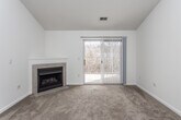 This single-floor residence is designed with an open, functional layout that connects the main living areas seamlessly. The living room is a comfortable, carpeted space highlighted by a corner fireplace with a classic tile surround, and a sliding glass door fitted with vertical blinds that admits natural light and provides outdoor access. Vaulted ceilings add a sense of height and openness to the living and dining area.

The kitchen runs alongside the living space, separated by a peninsula counter. It features white cabinetry, laminate countertops, hardwood-style flooring, a full suite of appliances including a refrigerator, range, and dishwasher, and ample storage along both sides of the galley-style layout.

The bedrooms are carpeted and include ceiling fans. The primary bedroom offers two closets, including a walk-in, while additional bedrooms feature windows that bring in natural light. Two bathrooms serve the home: one includes a tub-shower combination and tile flooring, while the other features a vanity with a wood-trimmed cabinet, a large mirror, and an overhead light bar. Throughout, the home maintains a neutral, light color palette that enhances its bright and clean atmosphere.
