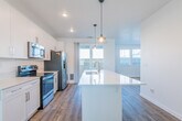 This well-designed two-story home offers a thoughtful layout with modern finishes throughout. The open-concept kitchen serves as the heart of the main floor, featuring crisp white cabinetry, light quartz countertops, and a full suite of stainless steel appliances including a range, microwave, and French door refrigerator. A generously sized center island with an integrated sink provides additional workspace and casual seating, while stylish pendant lighting adds a contemporary touch overhead. Recessed lighting and a sliding glass door leading to the outdoor patio fill the space with natural light. Adjacent to the kitchen, the living area continues the warm wood-look flooring and is brightened by multiple windows and a ceiling fan. A convenient powder room on the main level features a pedestal sink and mirror. Upstairs, the carpeted bedrooms offer a comfortable retreat, each equipped with ceiling fans and windows that bring in natural light and neighborhood views. Bedrooms are served by generous closet space, including a spacious walk-in closet with double hanging rods and shelving. A full bathroom upstairs includes a tiled tub-shower combination with chrome fixtures and wood-look flooring, completing this clean, move-in-ready home.