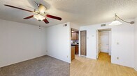 Located at 4181 North Granite Reef Road in Scottsdale, Arizona, this two-bedroom, one-bathroom unit offers a practical and functional single-level layout. The living room greets you at the entry with light hardwood-style flooring, a textured ceiling, and a window fitted with vertical blinds that allows natural light to filter in. The space transitions into carpeted areas, with a ceiling fan providing comfort throughout. The galley-style kitchen is efficiently designed with warm wood-tone cabinetry lining both walls, ample upper and lower storage, a stainless steel sink, and black appliances including a range and refrigerator. Light hardwood-style flooring runs through the kitchen, adding a clean, cohesive feel. Both bedrooms are carpeted and feature textured ceilings with ceiling fans. The primary bedroom is a well-proportioned room, while the secondary bedroom includes a window with vertical blinds offering views of surrounding greenery. A dedicated closet provides additional storage. The full bathroom includes a wood-tone vanity with a countertop sink and a separate water closet with a tub-shower combination. The overall aesthetic is clean, neutral, and move-in ready.