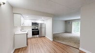 Located at 1547 W Irving Park Rd in Itasca, IL, this one-bedroom, one-bathroom residence offers a thoughtfully designed single-floor layout. The kitchen is outfitted with stainless steel appliances — including a refrigerator, electric range, and built-in microwave — complemented by white cabinetry, a white countertop, an undermount sink, and recessed lighting. Light wood-tone flooring runs through the kitchen and dining area, creating a clean, modern aesthetic that transitions seamlessly into the open living space. The living room features plush wall-to-wall carpeting, a baseboard heating system, a wall-mounted air conditioning unit, and a sliding glass door that opens to a private balcony with outdoor views of lush greenery. The bedroom is generously sized with carpeted floors, a wide window that draws in natural light, baseboard heating, and access to two closets — offering ample storage. A third closet is also available elsewhere in the unit. The full bathroom is finished in a crisp, all-white palette, featuring a vanity with white cabinetry and a large mirror, a tub/shower combination, and wood-tone flooring. Neutral gray walls throughout lend the space a cohesive, contemporary feel.