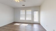 This single-floor unit offers a clean, functional layout designed for comfortable everyday living. The main living area is bright and open, featuring wood-look plank flooring, crisp white walls, and a ceiling fan with light fixture overhead. Large windows fitted with horizontal blinds allow abundant natural light to fill the space, and a door with a sidelight panel provides direct exterior access, further enhancing the airy atmosphere.

The kitchen is positioned at the rear of the living space and is defined by a raised peninsula that serves as a natural divider. Warm honey-toned cabinetry lines both walls of the galley-style kitchen, complemented by dark countertops and a full suite of black appliances, including an electric range, over-the-range microwave, dishwasher, and refrigerator. A stainless steel sink and additional storage complete the well-equipped cooking area.

The bedroom is a comfortable, carpeted room with a ceiling fan, white walls, and a window that admits natural light. The bathroom includes a full-size soaking tub and shower combination with clean white surround walls and chrome fixtures. Throughout the unit, consistent white trim and neutral finishes contribute to a cohesive, move-in-ready aesthetic.