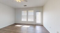 This single-floor unit offers a clean, functional layout designed for comfortable everyday living. The main living area is bright and open, featuring wood-look plank flooring, crisp white walls, and a ceiling fan with light fixture overhead. Large windows fitted with horizontal blinds allow abundant natural light to fill the space, and a door with a sidelight panel provides direct exterior access, further enhancing the airy atmosphere.

The kitchen is positioned at the rear of the living space and is defined by a raised peninsula that serves as a natural divider. Warm honey-toned cabinetry lines both walls of the galley-style kitchen, complemented by dark countertops and a full suite of black appliances, including an electric range, over-the-range microwave, dishwasher, and refrigerator. A stainless steel sink and additional storage complete the well-equipped cooking area.

The bedroom is a comfortable, carpeted room with a ceiling fan, white walls, and a window that admits natural light. The bathroom includes a full-size soaking tub and shower combination with clean white surround walls and chrome fixtures. Throughout the unit, consistent white trim and neutral finishes contribute to a cohesive, move-in-ready aesthetic.
