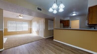 This single-floor residence at 2301 Arkansas Blvd in Texarkana, Arkansas offers a thoughtfully designed layout with comfortable living spaces throughout. The living area is a standout feature, highlighted by vaulted ceilings, a ceiling fan, and a charming white-mantled fireplace that serves as a focal point. Natural light pours in through multiple windows fitted with blinds, creating a warm and welcoming atmosphere. The flooring transitions from durable wood-look planks in the main living and dining areas to plush carpet in the bedrooms.

The kitchen is well-appointed with warm wood cabinetry, light countertops, and white appliances including a range, over-the-range microwave, and dishwasher. It opens to the dining area via a raised breakfast bar, making the space ideal for both everyday meals and entertaining. An elegant chandelier overhead adds a refined touch to the dining space.

Each bedroom is generously sized and carpeted, featuring ceiling fans and double-door closets offering ample storage. The two full bathrooms are finished with earthy stone-look tile flooring, wood vanities, and full tub-shower combinations, providing practical comfort. The overall color palette of warm beige tones throughout lends a cohesive and inviting feel to the entire home.