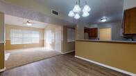 This single-floor residence at 2301 Arkansas Blvd in Texarkana, Arkansas offers a thoughtfully designed layout with comfortable living spaces throughout. The living area is a standout feature, highlighted by vaulted ceilings, a ceiling fan, and a charming white-mantled fireplace that serves as a focal point. Natural light pours in through multiple windows fitted with blinds, creating a warm and welcoming atmosphere. The flooring transitions from durable wood-look planks in the main living and dining areas to plush carpet in the bedrooms.

The kitchen is well-appointed with warm wood cabinetry, light countertops, and white appliances including a range, over-the-range microwave, and dishwasher. It opens to the dining area via a raised breakfast bar, making the space ideal for both everyday meals and entertaining. An elegant chandelier overhead adds a refined touch to the dining space.

Each bedroom is generously sized and carpeted, featuring ceiling fans and double-door closets offering ample storage. The two full bathrooms are finished with earthy stone-look tile flooring, wood vanities, and full tub-shower combinations, providing practical comfort. The overall color palette of warm beige tones throughout lends a cohesive and inviting feel to the entire home.