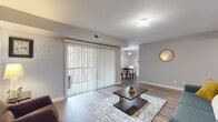 This single-floor residence offers a thoughtfully arranged layout connecting key living areas with a cohesive, modern aesthetic throughout. Warm-toned hardwood-style flooring runs continuously through the main living spaces, complementing the neutral gray walls that create a clean, versatile backdrop.

The living room is a comfortable, open space anchored by a large sliding glass door fitted with vertical blinds, providing direct access to an outdoor patio while allowing natural light to fill the room. A contemporary flush-mount light fixture overhead adds a modern touch. The space flows naturally into a separate dining area, which features a window with outdoor views and a stylish pendant light.

The kitchen is equipped with white shaker-style cabinetry, a subway tile backsplash, a stainless steel gas range, and a stainless steel sink, offering a functional and attractive cooking environment. Light wood-tone flooring keeps the space feeling bright and open.

Two bedrooms provide comfortable retreats, each featuring hardwood-style flooring, neutral walls, and ample space. One bedroom includes a walk-in closet. The full bathroom is well-finished with large-format dark tile flooring, a white vanity, and a tub-shower combination accented by striking stacked stone-style wall tile.