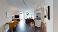 The Peach is a thoughtfully designed one-bedroom, one-bathroom unit located in Atlanta, GA. The open-concept living area flows seamlessly from the kitchen through the dining space into the living room, all unified by rich dark hardwood flooring and a clean, contemporary aesthetic. A curved architectural ceiling detail adds a distinctive design element to the main living space, which benefits from abundant natural light through large floor-to-ceiling glass doors that open to a private balcony with city views.

The kitchen is well-appointed with high-gloss white cabinetry extending to the ceiling, dark countertops, a full suite of stainless steel appliances including a side-by-side refrigerator, range, microwave, and dishwasher, plus a central island with bar seating. The living area comfortably accommodates a dining table and lounge seating.

The bedroom features direct balcony access through glass doors, continuing the city views, and is finished with the same dark hardwood flooring. The bathroom is a standout feature, showcasing a jetted soaking tub surrounded by large-format marble-style tile. Throughout, the unit maintains a bright, modern ambiance suited for comfortable urban living.