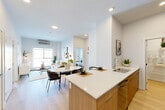 This well-appointed two-bedroom, two-bathroom unit in southwest Edmonton offers a thoughtfully designed, single-level layout with modern finishes throughout. The open-concept kitchen is a functional centerpiece, featuring warm wood cabinetry, stainless steel appliances, a wall-mounted range hood, and a white quartz peninsula with bar seating — ideal for both meal preparation and casual dining. Light wood flooring runs consistently throughout the unit, lending warmth and visual continuity across all spaces.

The living room is bright and inviting, anchored by a large sliding window that frames open outdoor views and provides direct access to a spacious balcony. The balcony overlooks a scenic pathway and surrounding neighborhood, offering open sightlines. A wall-mounted climate control unit ensures year-round comfort in the living area.

The bedrooms are clean and functional; the primary bedroom includes a built-in double closet and large windows that bring in ample natural light. Both bathrooms maintain a consistent modern aesthetic, with wood-toned vanities, white quartz countertops, and light flooring — one featuring a glass-enclosed shower, the other a tub-shower combination. The overall ambiance is clean, minimal, and contemporary.